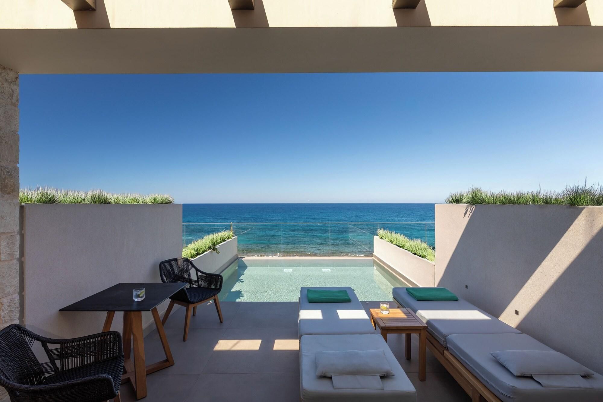 A rooftop terrace with a pool, lounge chairs, and a table with chairs.