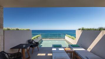 A rooftop terrace with a pool, lounge chairs, and a table with chairs.