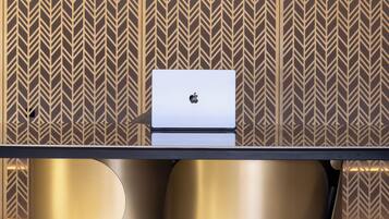 A modern room with a sleek table, a laptop, and a patterned wall.