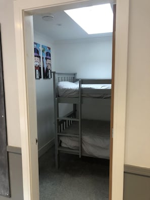 Ein Schlafraum mit Etagenbetten, einem Dachfenster, einer Tür und einer Wand mit Zeichentrickfiguren.