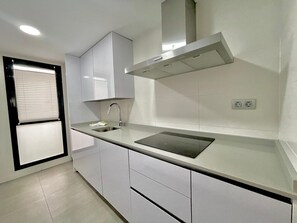 Een moderne keuken met witte kasten, een roestvrijstalen spoelbak en een zwart aanrecht.