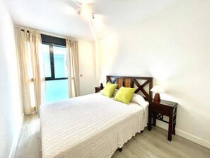 Ein Hotelzimmer mit einem Bett, einem Nachttisch, einer Lampe und einem Fenster mit Vorhängen.