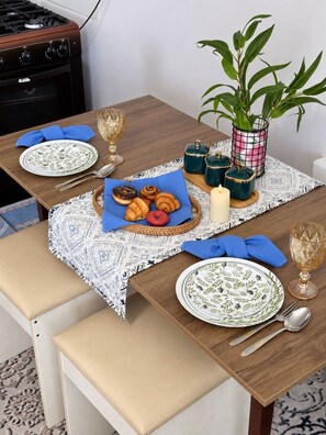 A dining table set with plates, cutlery, a candle, and a basket of pastries. - Zarafshan 60 (Tashkent)