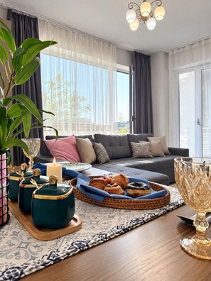 A modern living room with a sofa, a dining table with a candle, and a decorative plant. - Zarafshan 60 (Tashkent)
