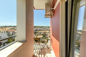 A balcony with a view of a residential area, a metal railing, and a window. - Caparica Sunny Apartment by Homing (Almada)