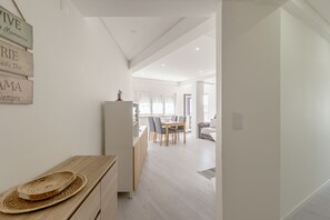 Una cocina moderna con un armario de madera, un refrigerador y una zona de comedor con mesa y sillas.