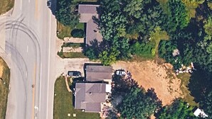 Luchtbeeld van een woonwijk met huizen, een weg en omliggend groen.