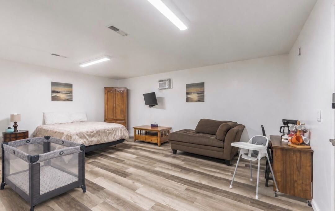 Une chambre à coucher comprenant un lit, un canapé, un parc pour bébé, une télévision et un bureau avec une chaise.