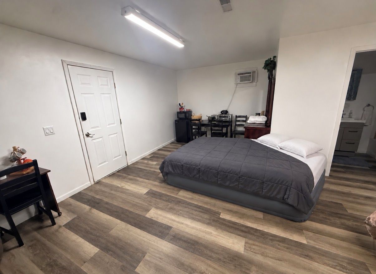 Een slaapkamer met een bed, bureau, stoel en kledingkast.