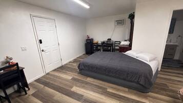 Een slaapkamer met een bed, bureau, stoel en kledingkast.