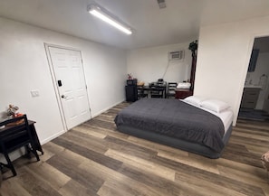 Un dormitorio con cama, escritorio, silla y armario.