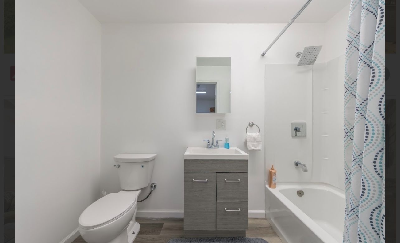 A modern bathroom with a toilet, vanity, and bathtub.