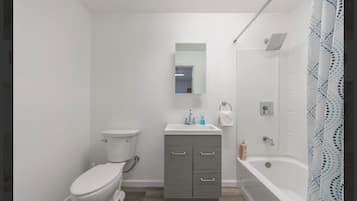 A modern bathroom with a toilet, vanity, and bathtub.