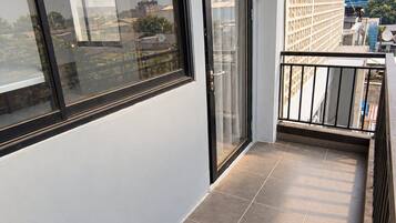 A balcony with a glass door and a view of the cityscape.
