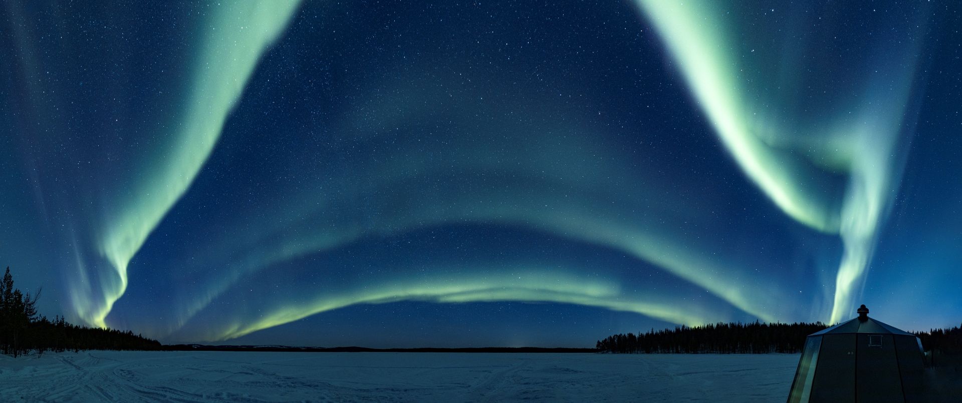 A snow-covered landscape with a clear night sky and the Northern Lights.
