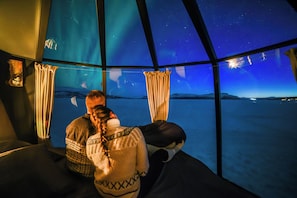 A room with a starry night view through a large window, a bed, and curtains. - Peace & Quiet Hotel Kiruna (Kiruna)