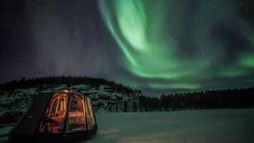 A snow-covered landscape with a tent-like structure and a view of the northern lights.