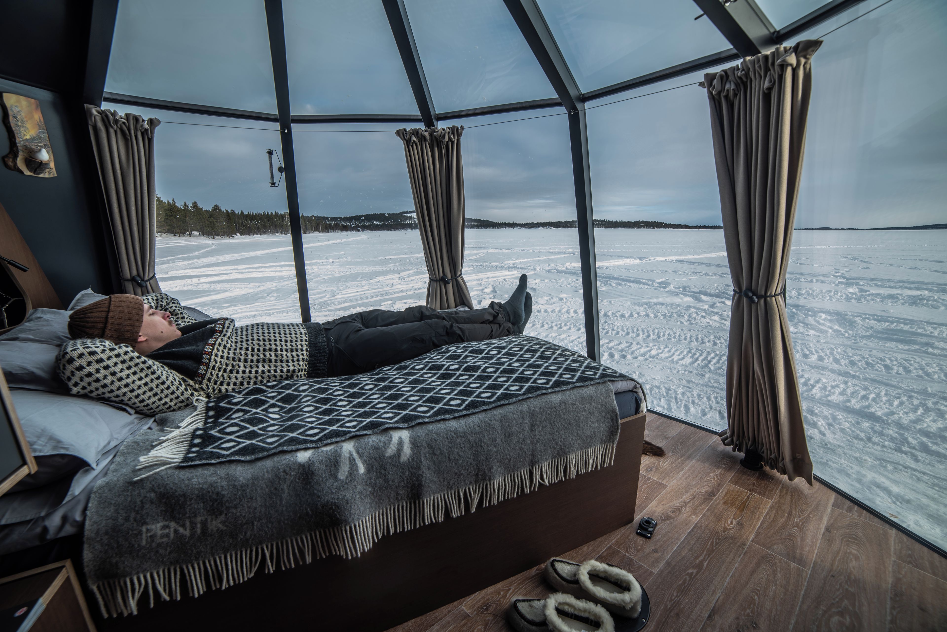 A room with a bed, a window, and a view of a snowy landscape.