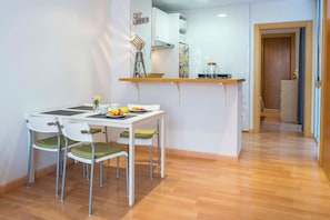Una cocina compacta con zona de comedor, que incluye una pequeña mesa con sillas, una encimera y un mueble con un diseño colorido.