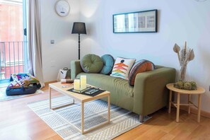 A cozy living room with a green sofa, a small wooden coffee table with candles, a lamp, and a framed picture on the wall. - Casa Picaso by Sharinco (Málaga)