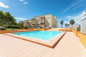 A swimming pool with a tiled deck, surrounded by buildings with balconies, under a clear sky. - Cap Agde Waterfront (Agde)