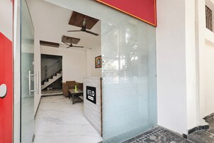 Ein Hotel-Empfangsbereich mit Glastrennwand, einem Schild mit der Aufschrift 'HOTEL' und einer Treppe, die zu einer oberen Etage führt.