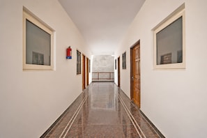A corridor with a marble floor, wooden doors, and a fire extinguisher on the wall. - Super Hotel O Gorakhpur Railway Junction (Gorakhpur)