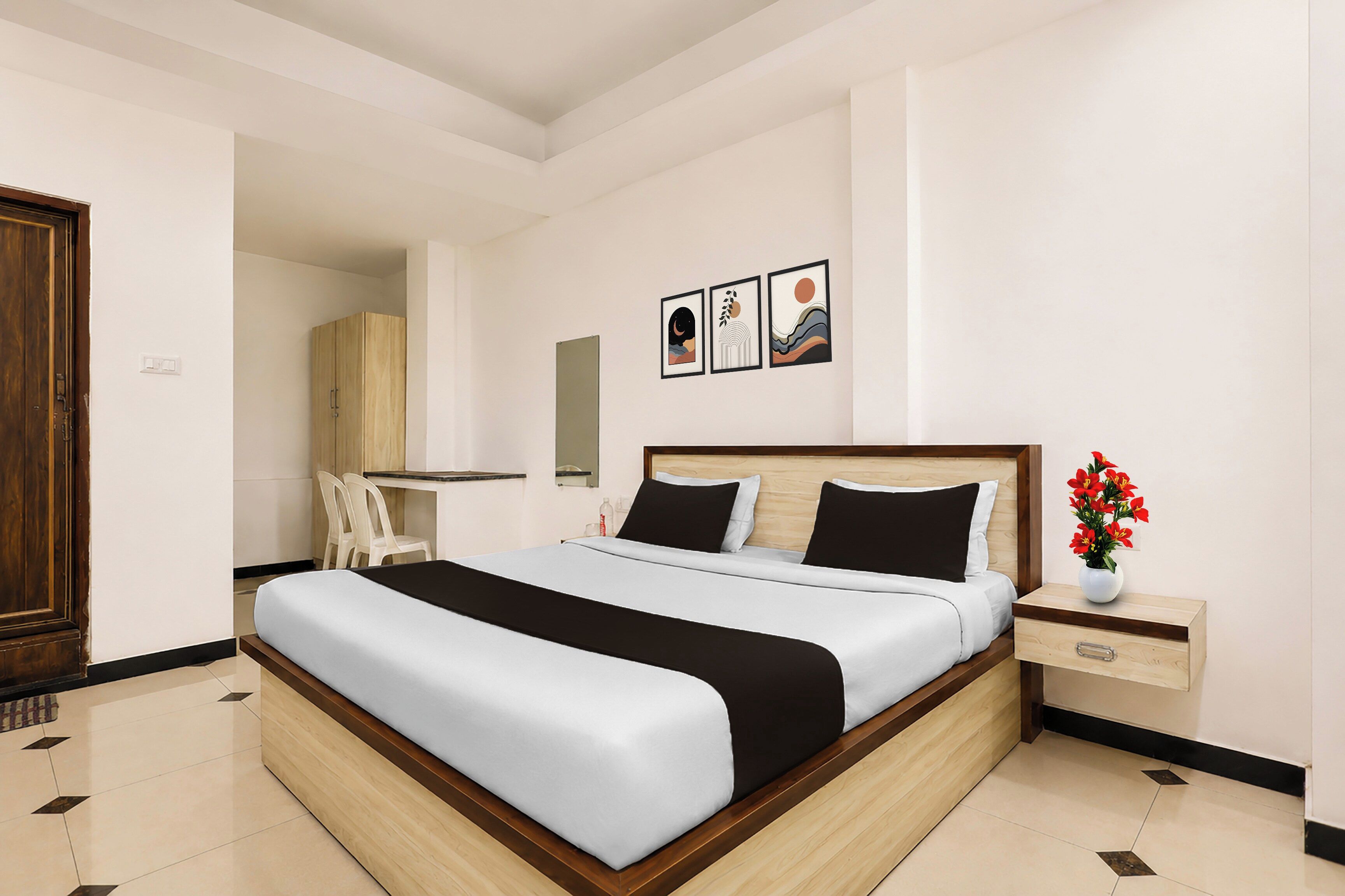A modern bedroom with a large bed, a bedside table with a vase of flowers, and a wardrobe.