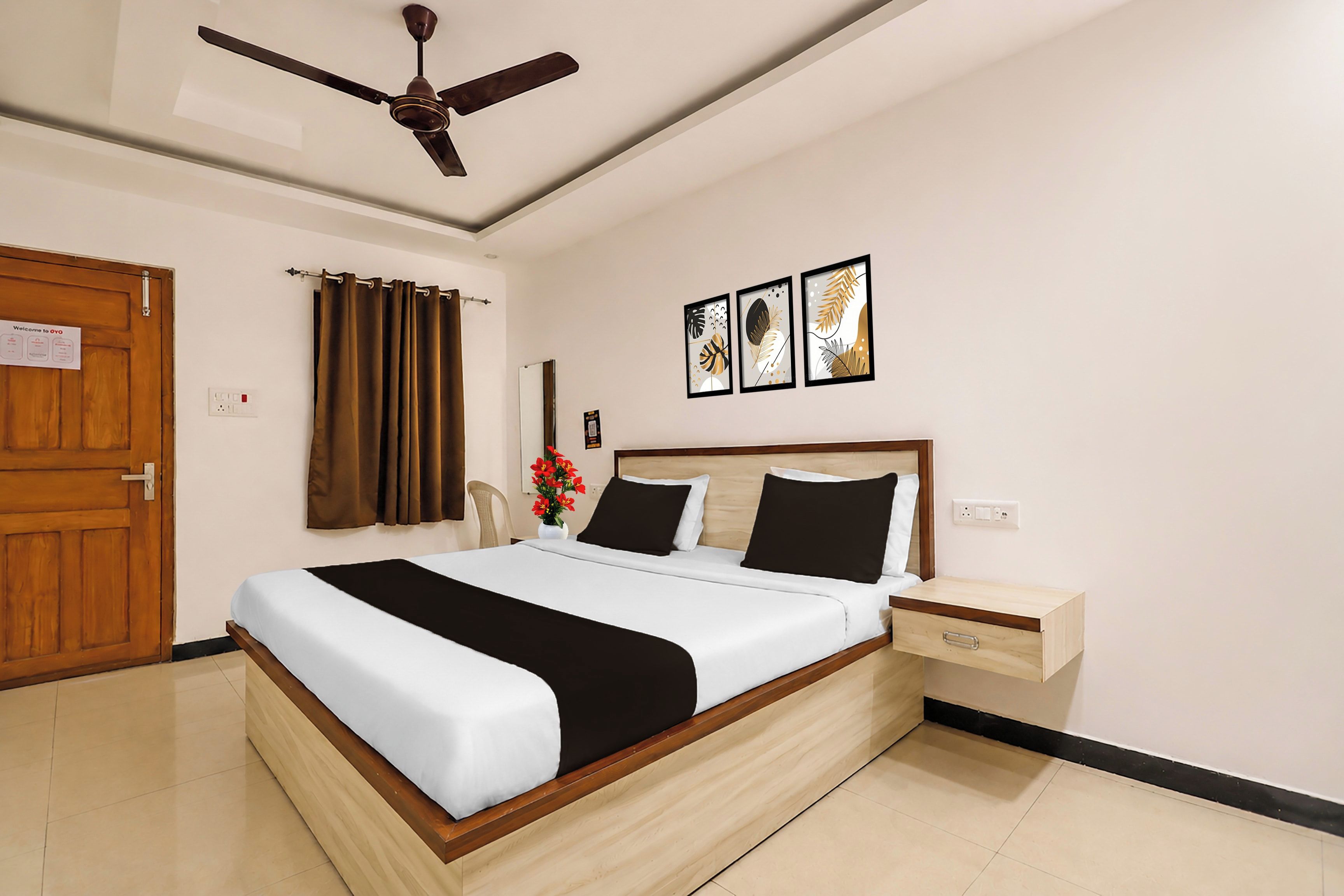 Habitación de hotel con cama, mesita de noche, ventilador de techo y una puerta.