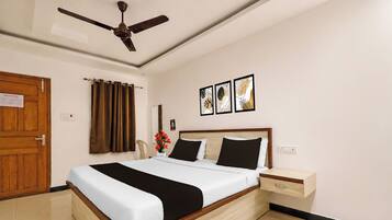 Habitación de hotel con cama, mesita de noche, ventilador de techo y una puerta.