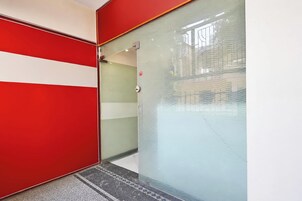 Ein Korridor mit roter und weißer Wand, einer Glastür und einem gefliesten Boden.