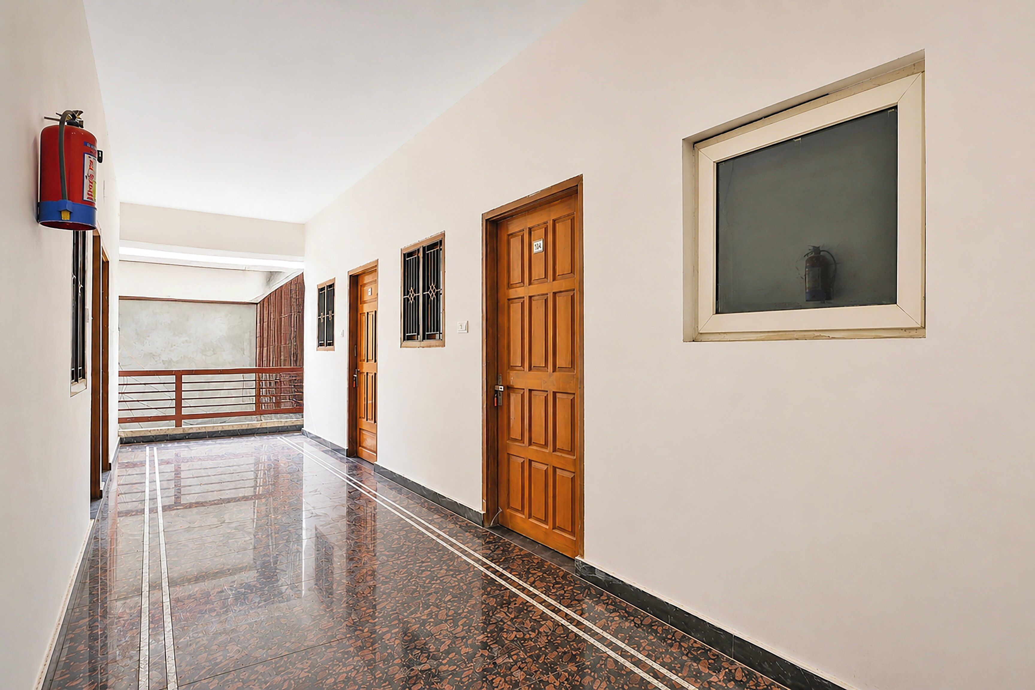 Un pasillo con puertas de madera, un extintor y una ventana con vistas.