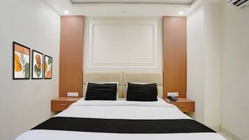 Habitación de hotel con una cama, dos mesitas de noche, un teléfono y cuadros en la pared.