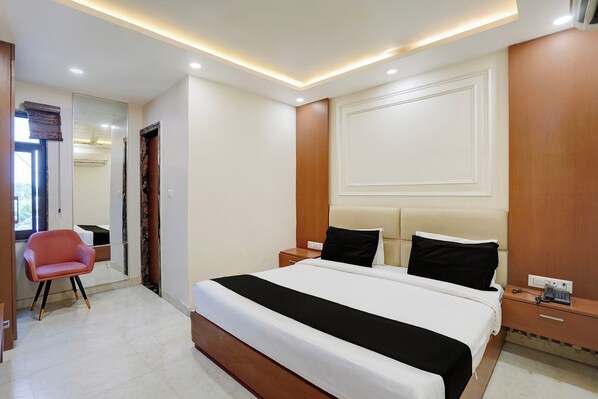 Une chambre d’hôtel avec un grand lit, des tables de chevet, une chaise et un miroir.
