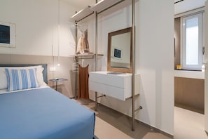 A modern hotel room with a bed, a vanity with a mirror, and a window. - Charming sea front apartment with terrace in Mazzarò, Taormina - DICasaInSicilia (Taormina)