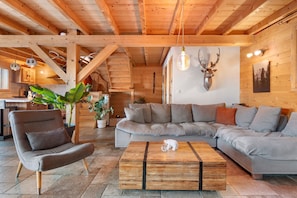 A cozy living room with a wooden ceiling, a sofa, a coffee table, and a mounted deer head. - Chalet 'Chalet des Loutres' at the foot of the slopes and chairlift, peaceful, panoramic view (Les Deux Alpes)