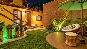 A well-lit outdoor area with a wooden staircase, a green umbrella, and a seating area with a cushion.