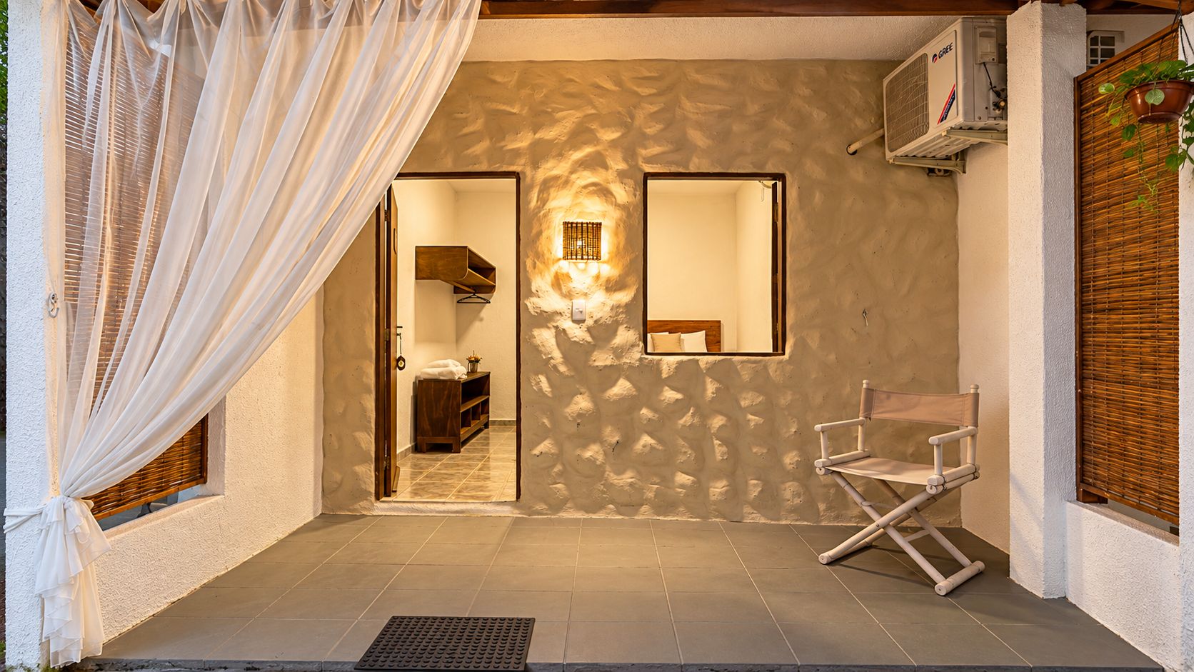 Una habitación con cama, una silla, un espejo y una ventana con cortinas.