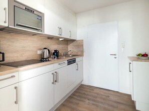 A modern kitchen with white cabinets, a stainless steel oven, and a wooden countertop. - Holiday Apartment in Norderney With Sauna (Norderney)
