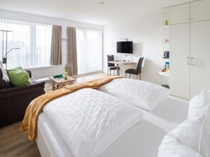 A hotel room with a bed, a desk, a chair, a television, and a wardrobe. - Holiday Apartment in Norderney With Sauna (Norderney)