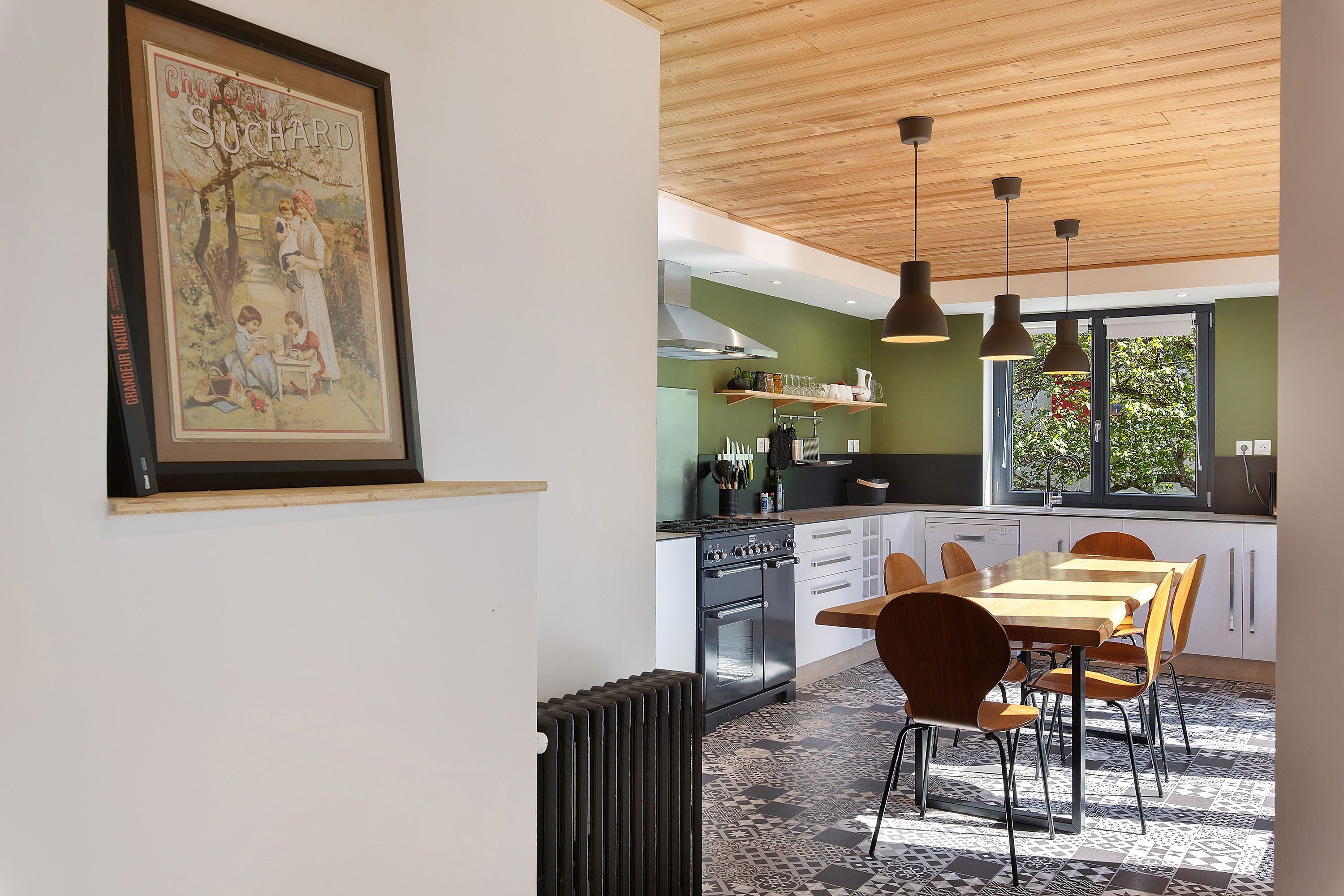 Une cuisine moderne avec un coin repas, comprenant une cuisinière, un four et des luminaires suspendus.
