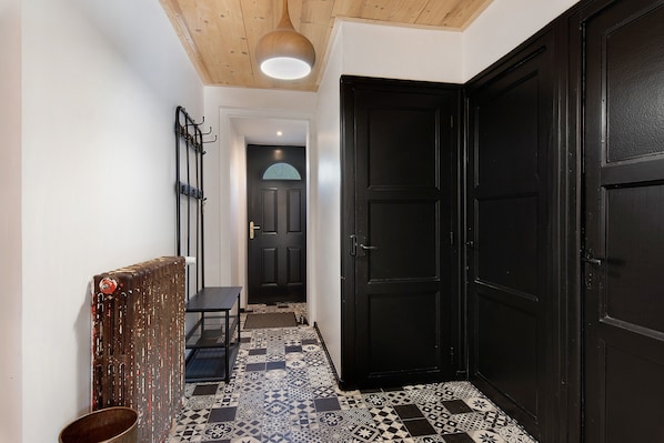 A hallway with a black door, a coat rack, and a radiator.