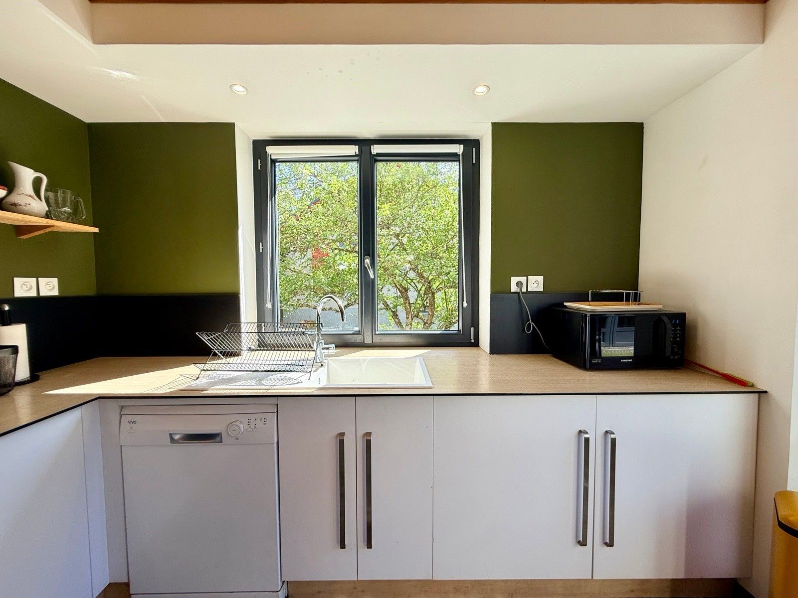 A modern kitchen with a dishwasher, double sink, and a microwave.