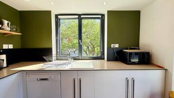 A modern kitchen with a dishwasher, double sink, and a microwave.