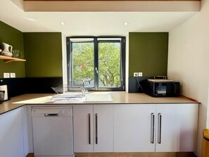 Cocina moderna con lavavajillas, pileta doble y microondas.
