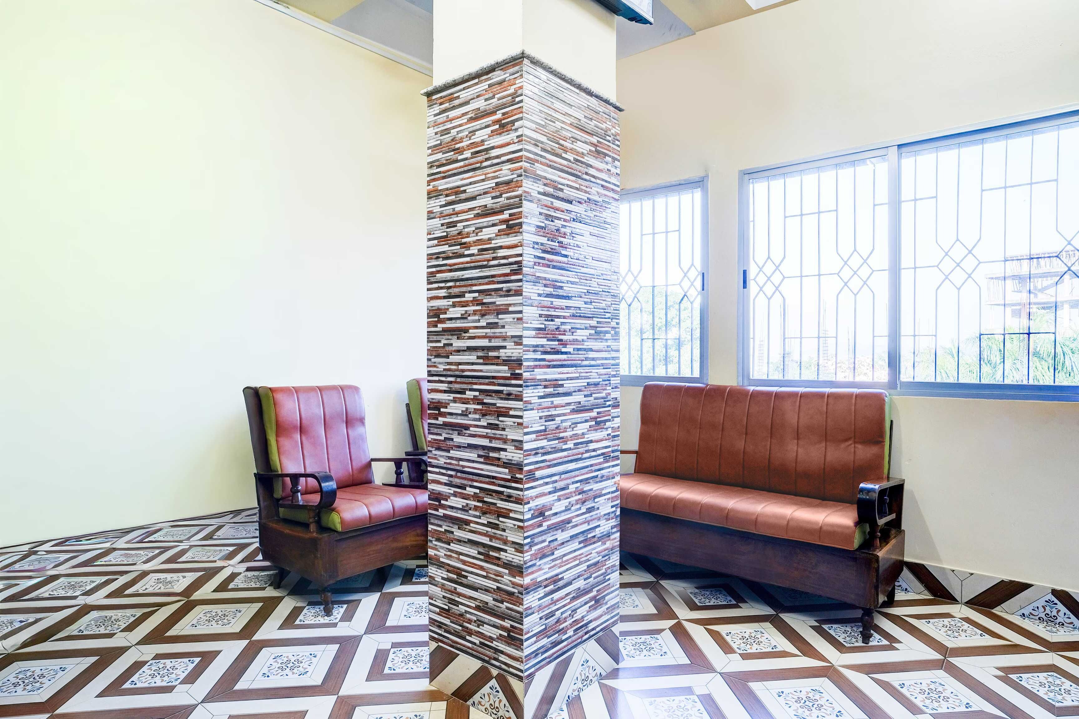 A room with a patterned floor, a stack of books against a wall, and two leather sofas.