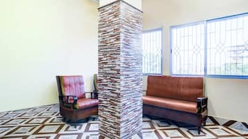 A room with a patterned floor, a stack of books against a wall, and two leather sofas.