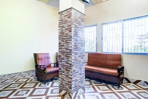 Una habitación con piso estampado, una pila de libros contra la pared y dos sofás de cuero.