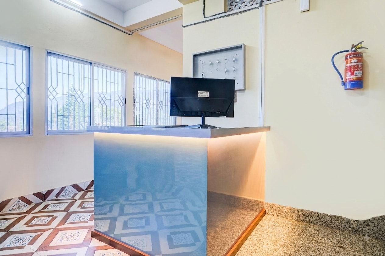 Una reception con un monitor per computer, un estintore e un pannello di controllo a parete.
