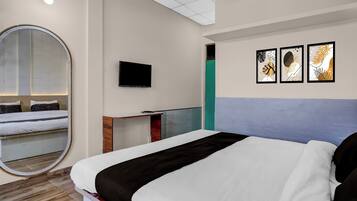 Habitación de hotel con cama, escritorio, televisor y obras de arte en la pared.